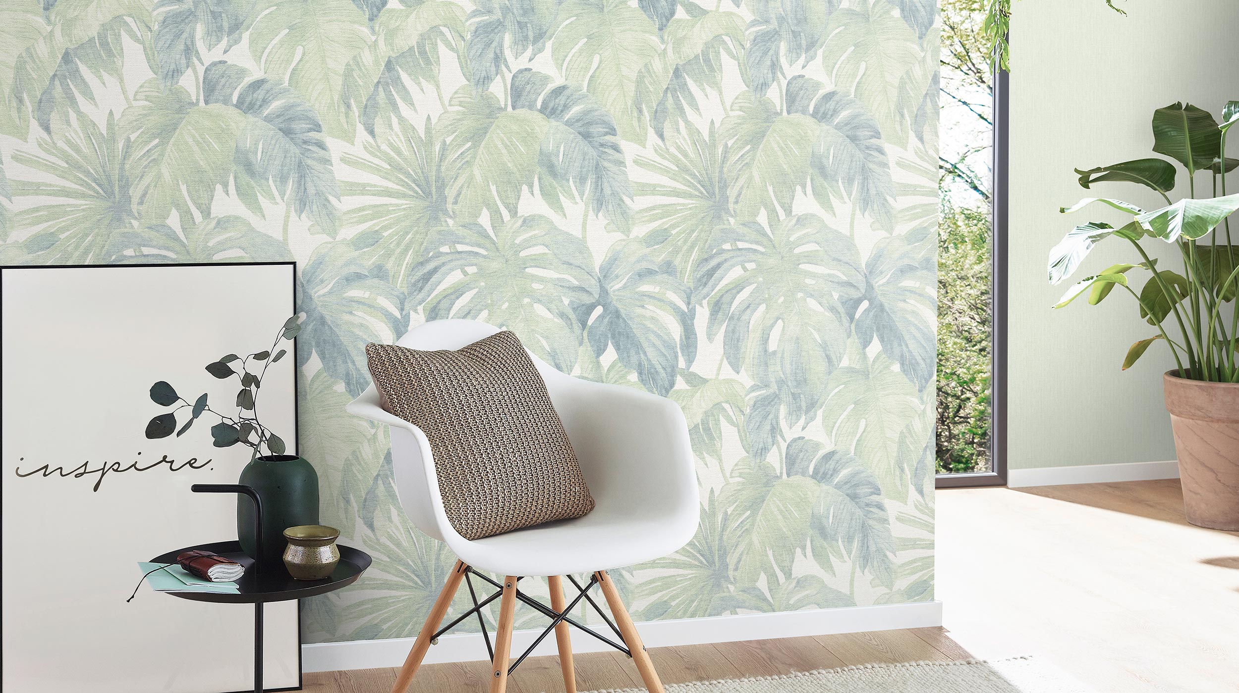 moderner Wohnraum mit weißem Stuhl und Vliestapete mit Monstera Blättern in blassem grün 