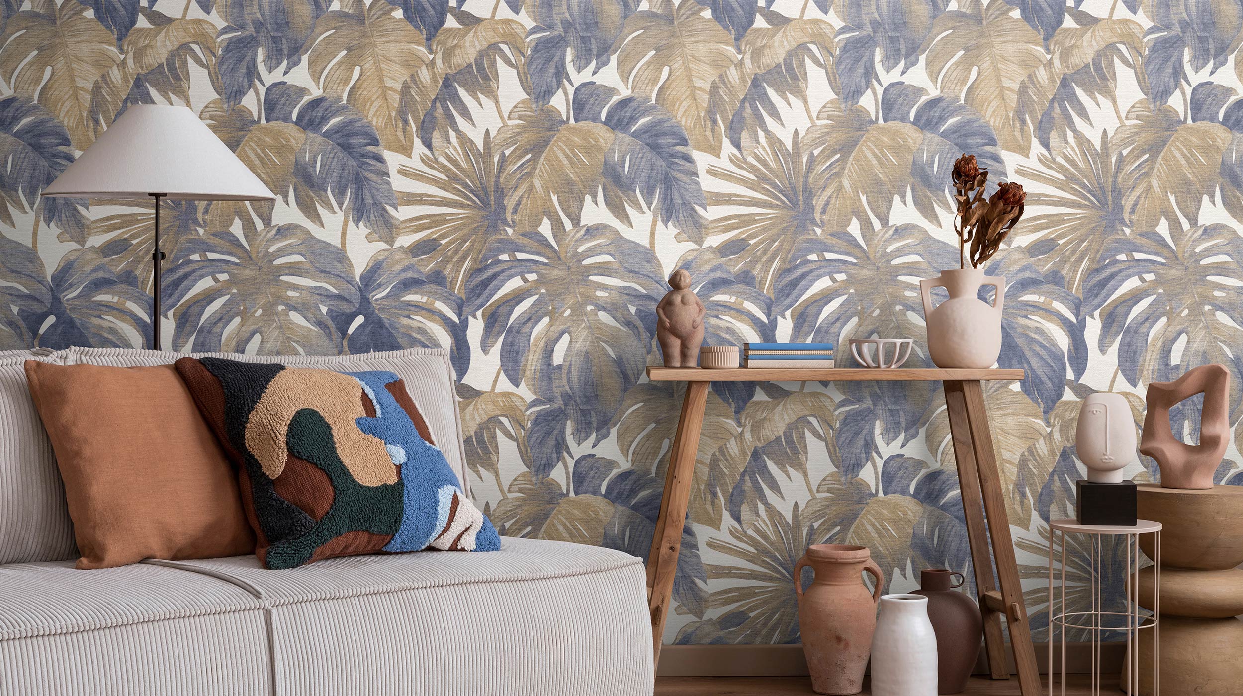 moderner Wohnraum mit Sofa und Vliestapete mit Monstera Blättern in blassem blau und braun