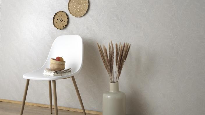 cremefarbene Vliestapete mit Blättermotiv, weißer Stuhl und Accessoires im Boho-Look