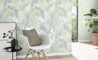 moderner Wohnraum mit weißem Stuhl und Vliestapete mit Monstera Blättern in blassem grün 