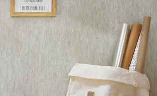 Vlietapete mit versteinert wirkender Holzrindenstruktur in einem hellen Grau 