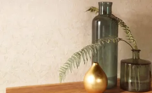 Vliestapete in einem zarten beige, die durch goldene metallic Effekte an der Wand wie Gold wirkt