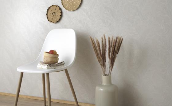 cremefarbene Vliestapete mit Blättermotiv, weißer Stuhl und Accessoires im Boho-Look